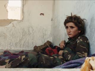 chlapec sedí na dece a opírá se o omšelou zeď