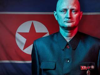 muž v uniformě stojí před vlajkou