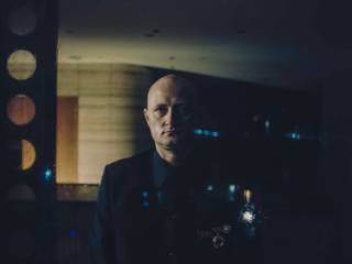 vážný muž stojí v tmavé místnosti