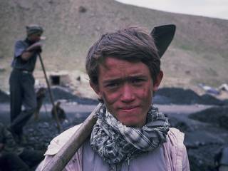 chlapec se zašpiněným obličejem hledí do kamery