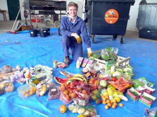 žena klečící nad velkým množství potravin zachráněných z popelnice