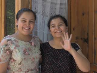 dvě ženy  se usmívají do kamery, jedna mává