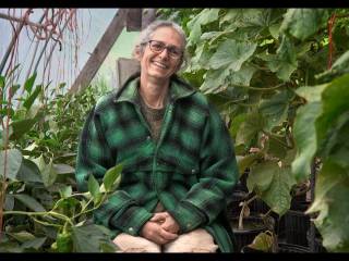 usmívající se žena sedí uprostřed zeleně skleníku